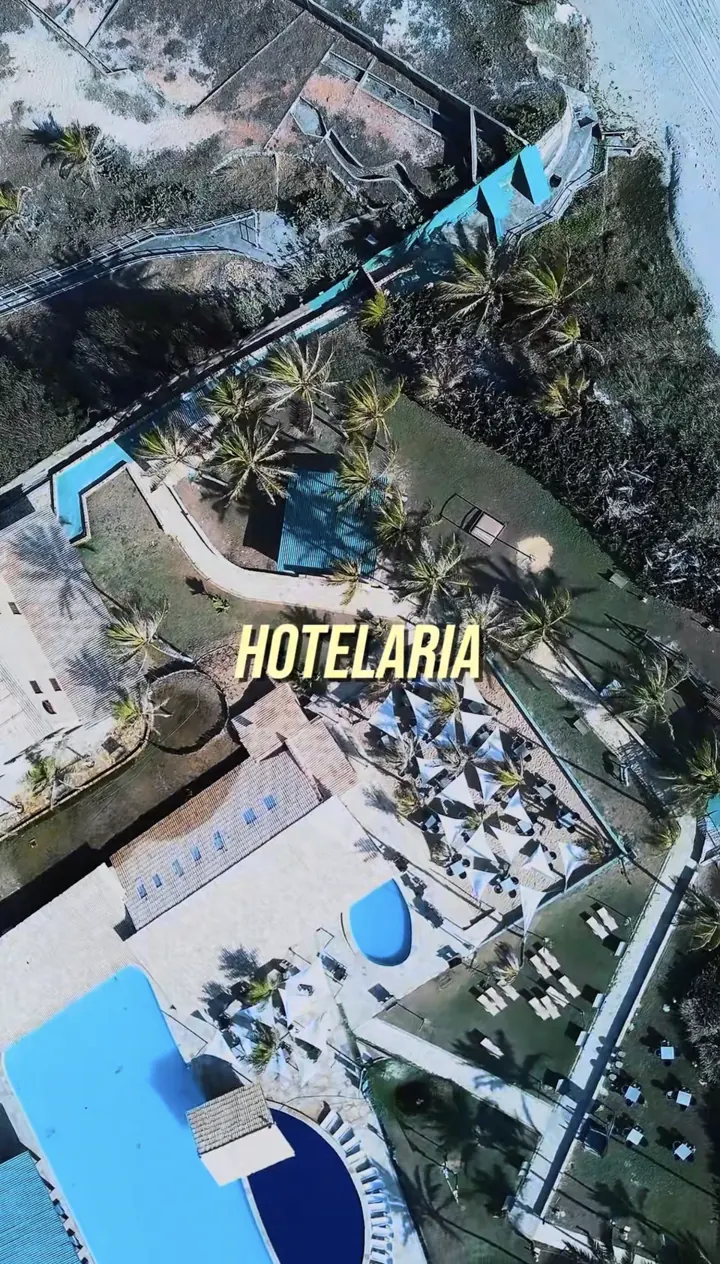 Vista aérea de resort com piscinas, jardins e áreas de convivência que podem receber áudio distribuído.